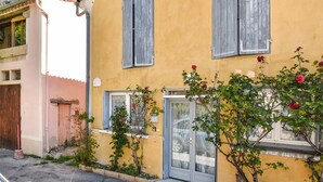 A yellow building with two windows and a door, surrounded by greenery and roses. - 1 bedroom cozy home in Moustiers-Sainte-Marie (Moustiers-Sainte-Marie)