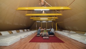 A tent-like room with multiple beds, a central table with a plant, and a red rug. - Wind's House Ha Giang (Vi Xuyen)