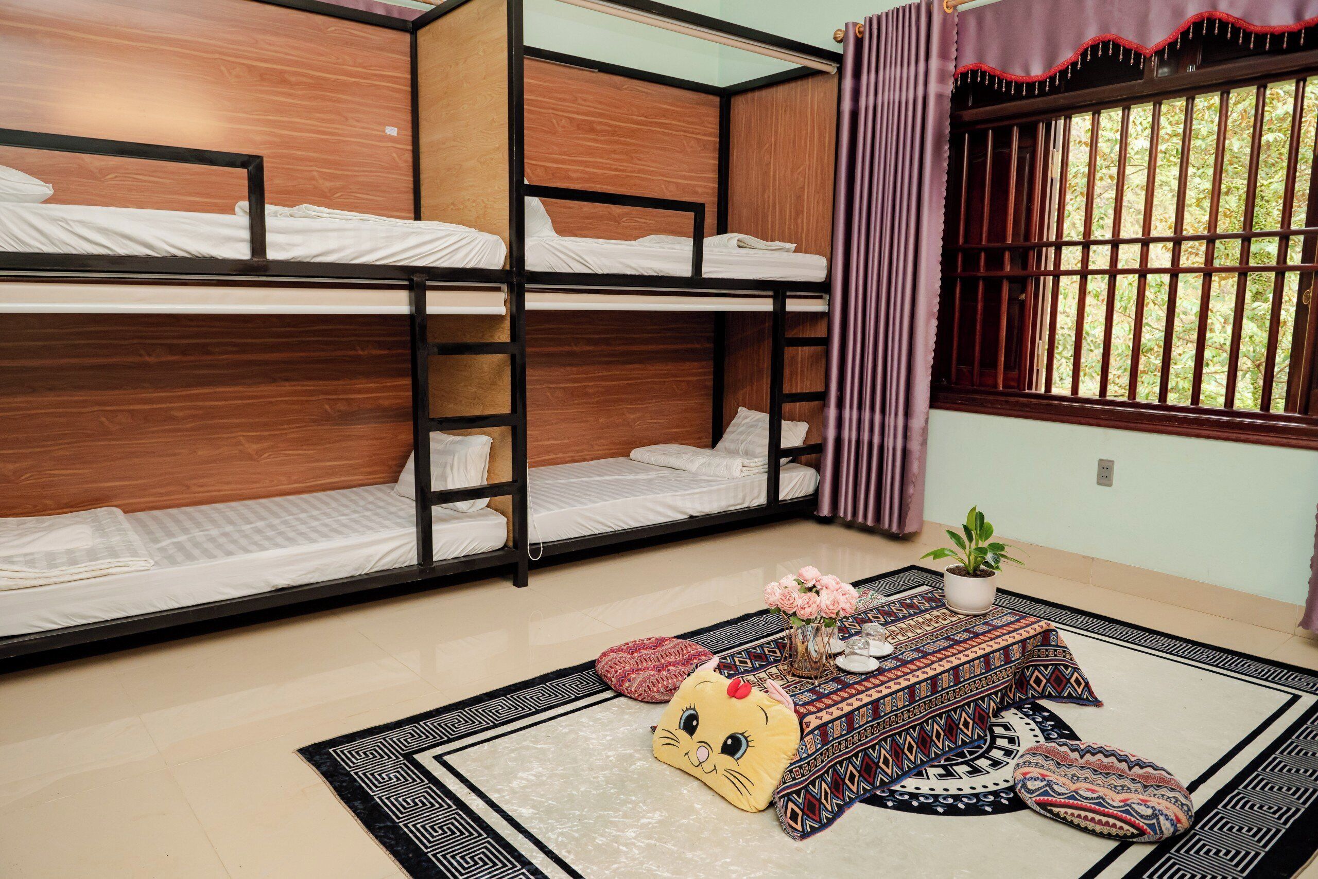 A room with bunk beds, a small table with a plant, and a decorative cushion.