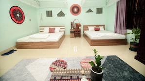 A room with two beds, a desk, and a chair. There are decorative pillows and a potted plant. - Wind's House Ha Giang (Vi Xuyen)