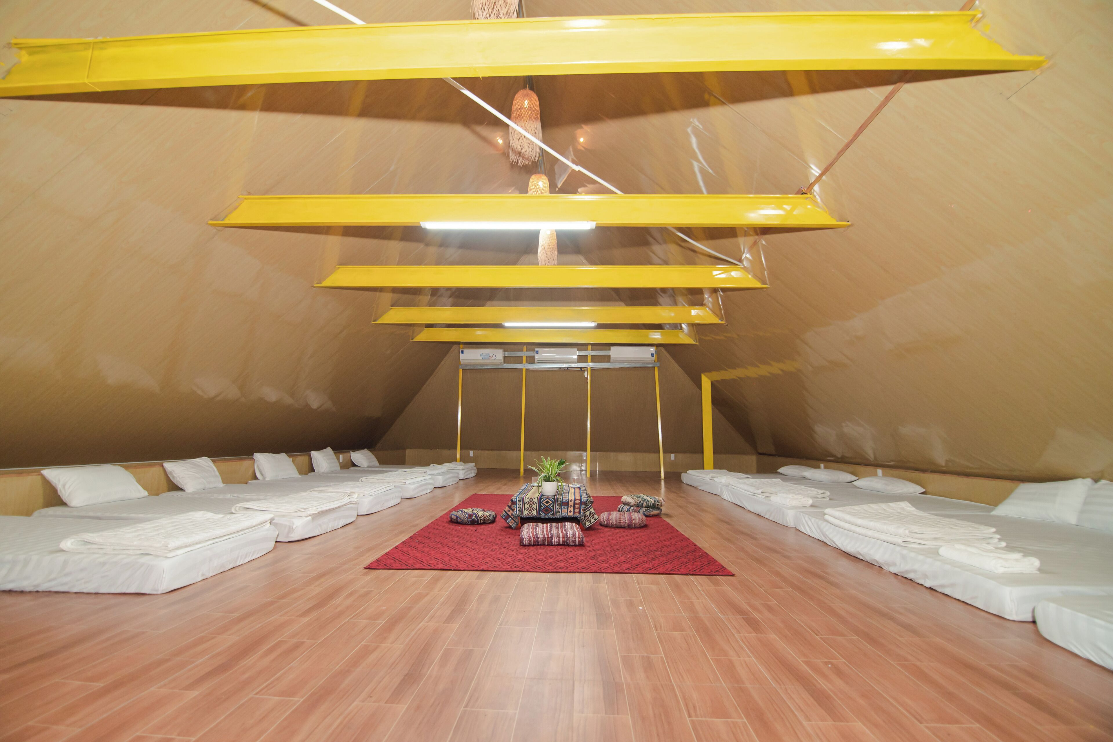 A spacious room with a high ceiling, wooden flooring, and a central area with a red rug.