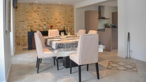A dining area with a stone wall, a kitchen in the background, and a patterned rug. - 3 bedroom nice home in Saint Robert (Saint Robert)
