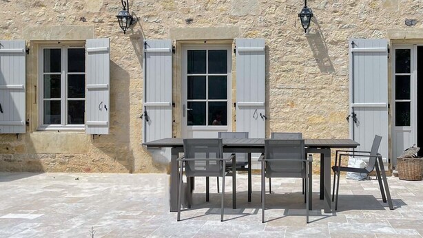 An outdoor patio with a table and chairs, stone walls, and shutters. - 3 bedroom nice home in Saint Robert (Saint Robert)