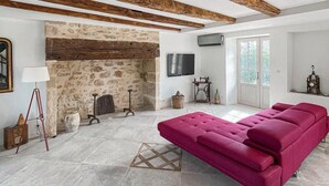 A modern living room with a stone fireplace, a flat-screen TV, a red sofa, and a wooden ceiling. - 3 bedroom nice home in Saint Robert (Saint Robert)