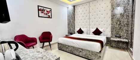 Una habitación de hotel moderna con una cama, dos sillas rojas, una encimera de mármol y un ventilador de techo.