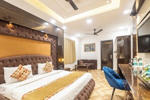 Quarto de hotel com uma cama grande, um sofá, uma mesa pequena e uma televisão.