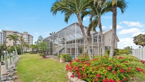 A modern house with a glass-enclosed porch, surrounded by a well-maintained lawn and a stone border.