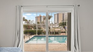A bedroom with a sliding glass door leading to a pool area.