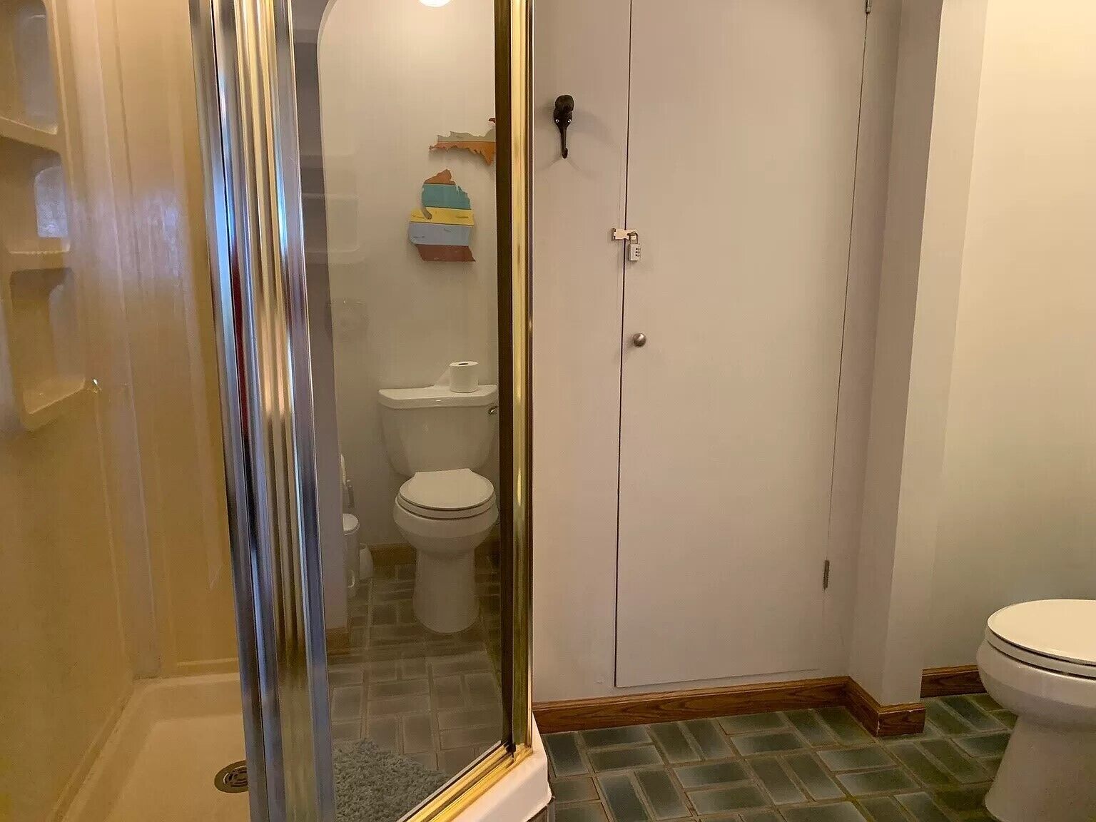 Un baño con cabina de ducha de vidrio, inodoro y un mueble con artículos de aseo.