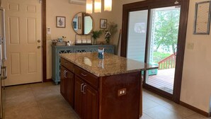 Una cocina con encimera de granito, armarios de madera, un lavabo doble y un amplio ventanal con vistas al exterior.