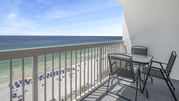 A balcony with a view of the beach and ocean.