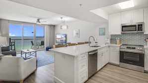 A modern kitchen with white cabinetry, a built-in oven, and a large island with a sink.