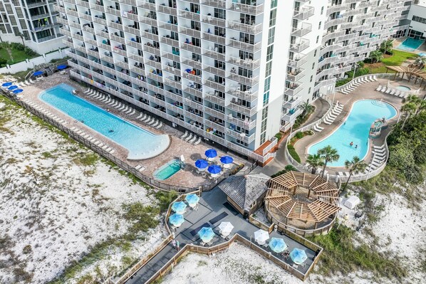 A high-rise hotel with multiple balconies, a central swimming pool, and a smaller pool area.