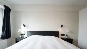 A hotel room with a large bed, two bedside tables with lamps, and a window with curtains. - 't Zout with balcony by Interhome (Bredene)