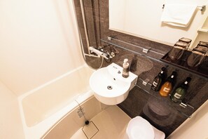 A bathroom with a bathtub, a sink, and a toilet. There are bottles of toiletries on the counter.