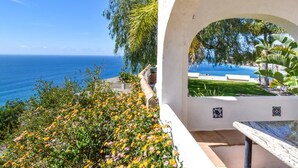 A patio with a view of the ocean, surrounded by greenery and a white wall with a tiled design. - Villa with private pool, the best sea views. (Almuñécar)