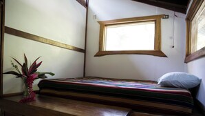 A small, cozy room with a single bed, a wooden bench, and a window providing natural light. - VerdEnergia  (Mercedes Sur)