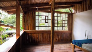 A wooden room with a large window, a bed, and a bench. - VerdEnergia  (Mercedes Sur)