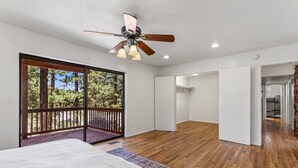 Quarto com cama grande, ventilador de teto e vista para o exterior através de uma porta de correr.