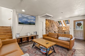 A living room with a wooden bench, a leather sofa, a coffee table, and a wall-mounted TV.