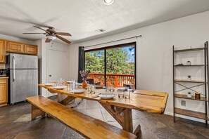 A kitchen with a dining table set for four, a refrigerator, and a view of a balcony with a railing.