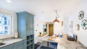 Eine moderne Küche mit Marmorarbeitsplatte, einem blauen Schrank und einer Bar mit Sitzgelegenheiten.