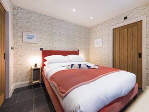 Cozy retreat with a unique architectural design, featuring a large bed and a wooden door.