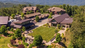 A resort with multiple buildings, a central courtyard, and a mountainous backdrop. - Mountain Kandy - Luxury home with stunning views and amenities! (Boone)