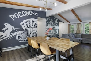 A modern living space with a dining area, a sofa, and a wall mural.