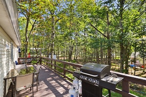 Une terrasse dotée d’un barbecue, de mobilier d’extérieur et offrant une vue sur une zone boisée.