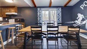 Un comedor con mesa y sillas de madera, una cocina con gabinetes de madera y un ventanal con cortinas estampadas.
