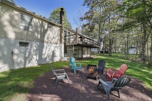 Un patio trasero con una chimenea, asientos exteriores y una terraza de madera.