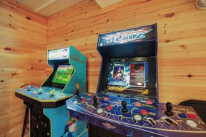 Two arcade gaming machines with 'NFL Blitz' and 'The Simpsons' titles, set against a wooden wall.