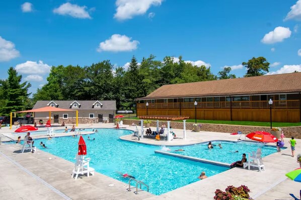 Un espace piscine comprenant plusieurs bassins, des chaises longues et des parasols.