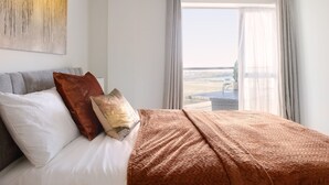 Een hotelkamer met een bed, uitzicht en een raam met gordijnen.