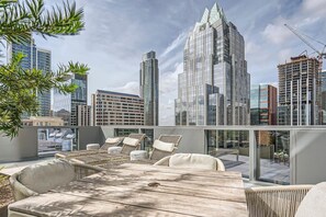 Relax on the rooftop terrace with a panoramic view of the city skyline, featuring a table and lounge chairs.