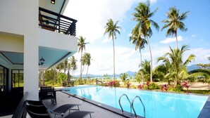 A pool area with lounge chairs, a view of palm trees, and a clear sky. - El Nido Palms Resort (El Nido)