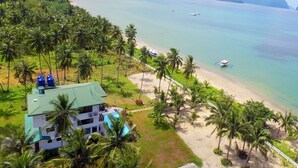 A beachfront property with a pool, surrounded by palm trees and a view of the ocean. - El Nido Palms Resort (El Nido)