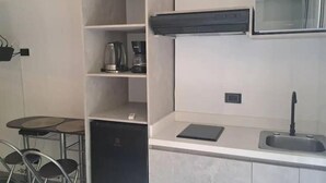 Una cocina moderna con lavavajillas incorporado, cafetera y un pequeño mostrador con fregadero.