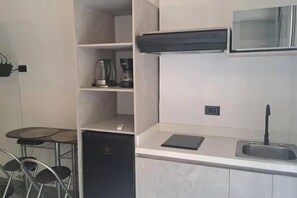 Eine moderne Küche mit eingebautem Geschirrspüler, einer Kaffeemaschine und einer kleinen Arbeitsplatte mit Spüle.