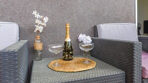 A wicker sofa with a woven placemat, a bottle of champagne, and a glass on a table. - Les Balcons d'Eze by Interhome (Eze)