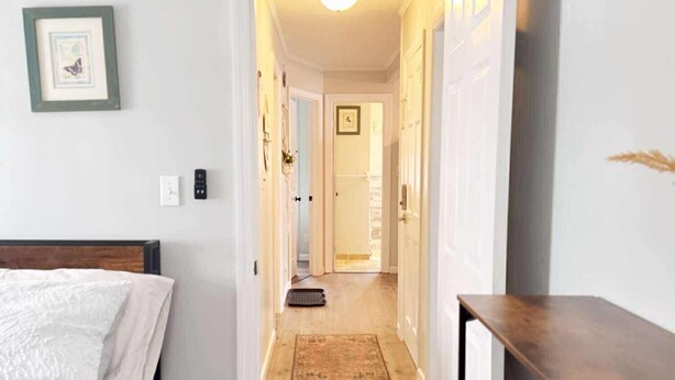 Un dormitorio con cama, cómoda, pasillo que conduce a otra habitación y una puerta al final.