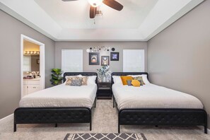 A bedroom with two beds, a ceiling fan, and a vanity with lights. - Contemporary Rustic Luxe Retreat - Near FT Moore (Columbus)