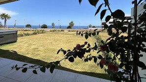 Une terrasse avec vue sur la mer, une pelouse et un bâtiment en arrière-plan.