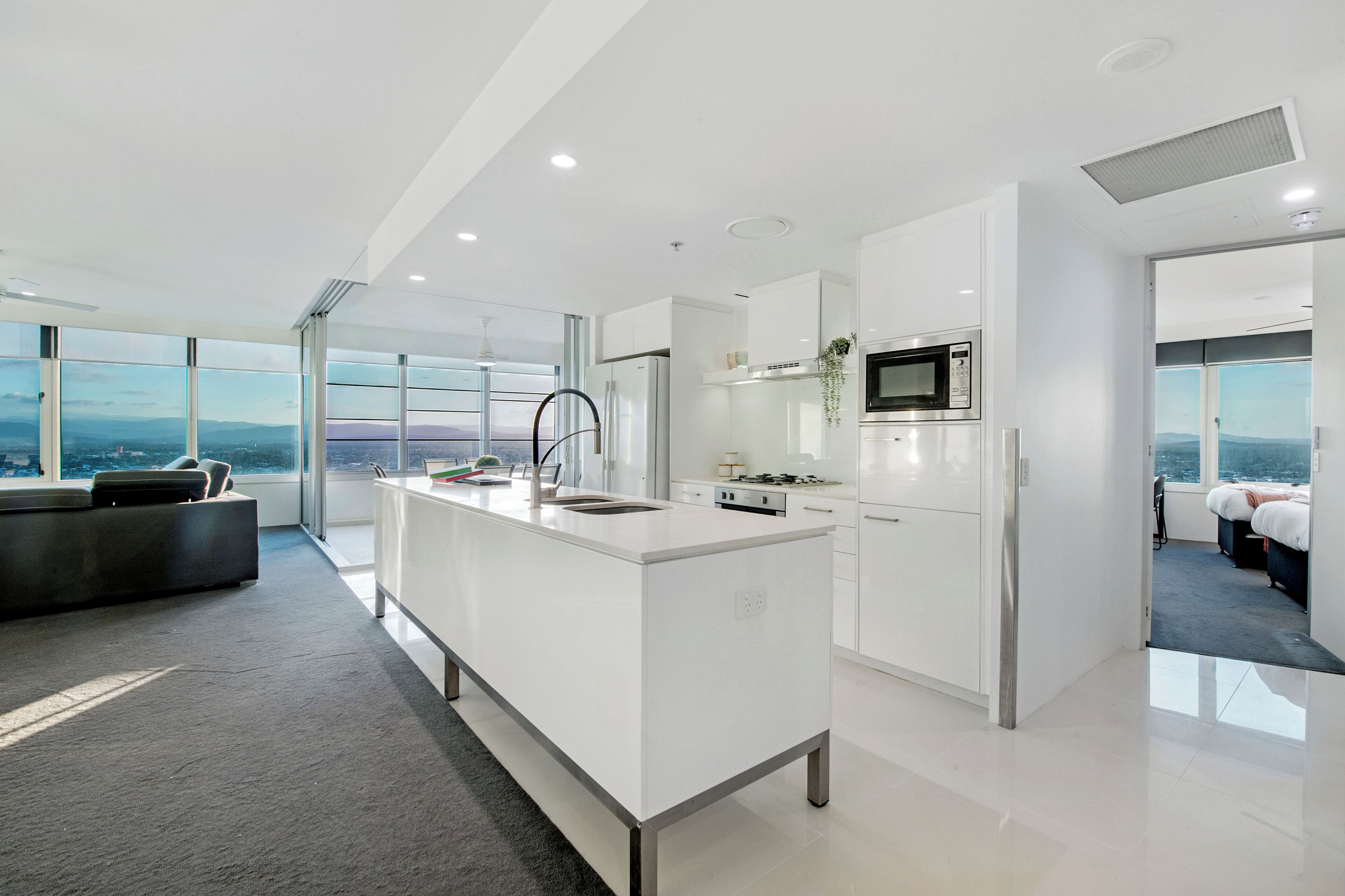 Una cocina moderna con una isla grande, armarios blancos y vistas a la ciudad.