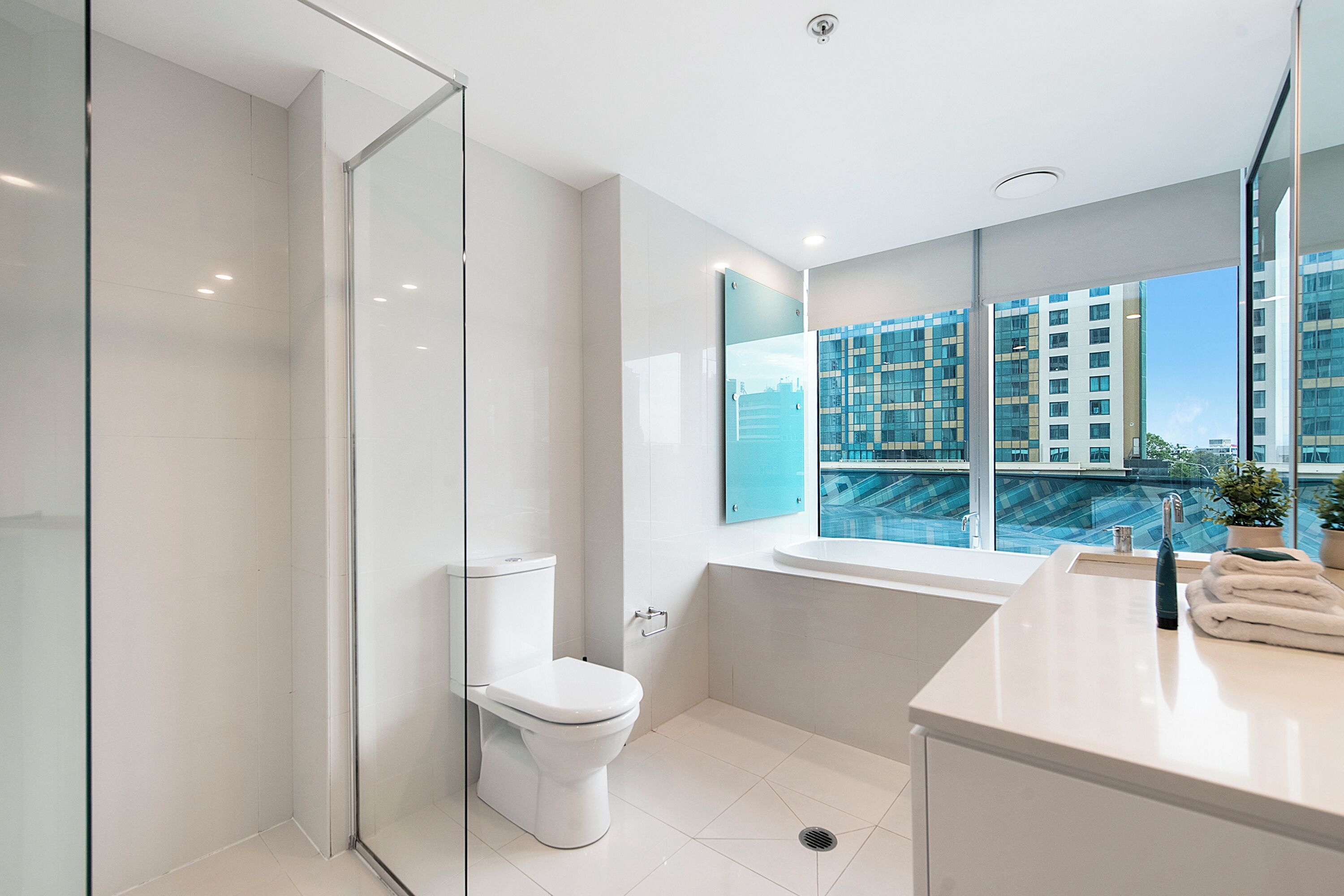Une salle de bain moderne avec une douche à parois de verre, des toilettes blanches, une baignoire et un lavabo avec un miroir.