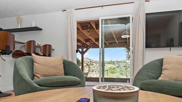Una habitación con dos sofás verdes, una mesa de madera con un control remoto y un televisor en la pared.