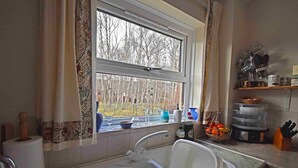 A kitchen with a window, sink, and various kitchen items on the counter. - Birch View -  Retreat Group (Aviemore)