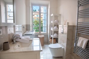 A bathroom with a sink, toilet, and a window with a view of buildings. - Saint Michel - Apartment in Old Town, Menton, France (Menton)