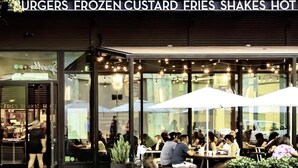 A restaurant named 'SHAKE SHACK' with outdoor seating and string lights.